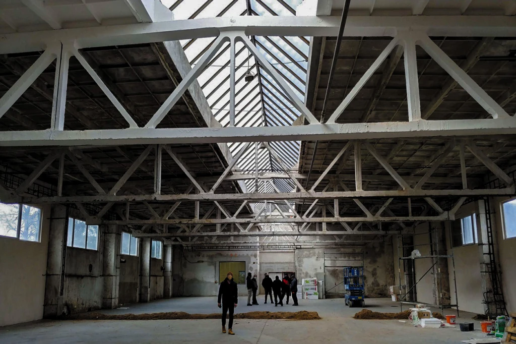 Interior of an industrial hall roofed with segmented ZIPP concrete trusses of type SPP 6-18/6: the truss webs have vertical members as well as diagonals, with pairs of verticals at the segment joints