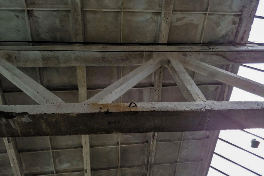 Underside of a segmented concrete truss where two segments meet: two vertical members standing side by side and a joint line running across the bottom chord