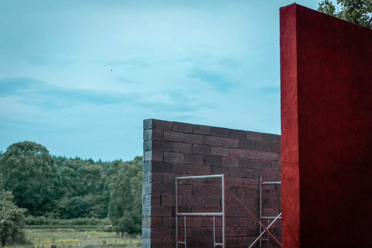 Red rendered wall meeting grey blockwork against the sky