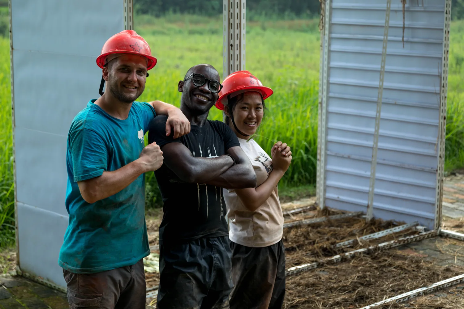 Three students in helmets posing together on site